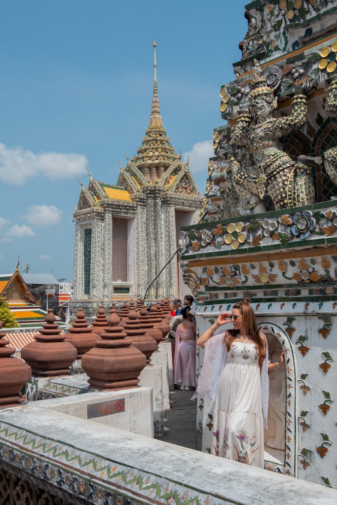 Woman in a white dress at Wat Arun temple, with its porcelain spires, in Bangkok, Thailand