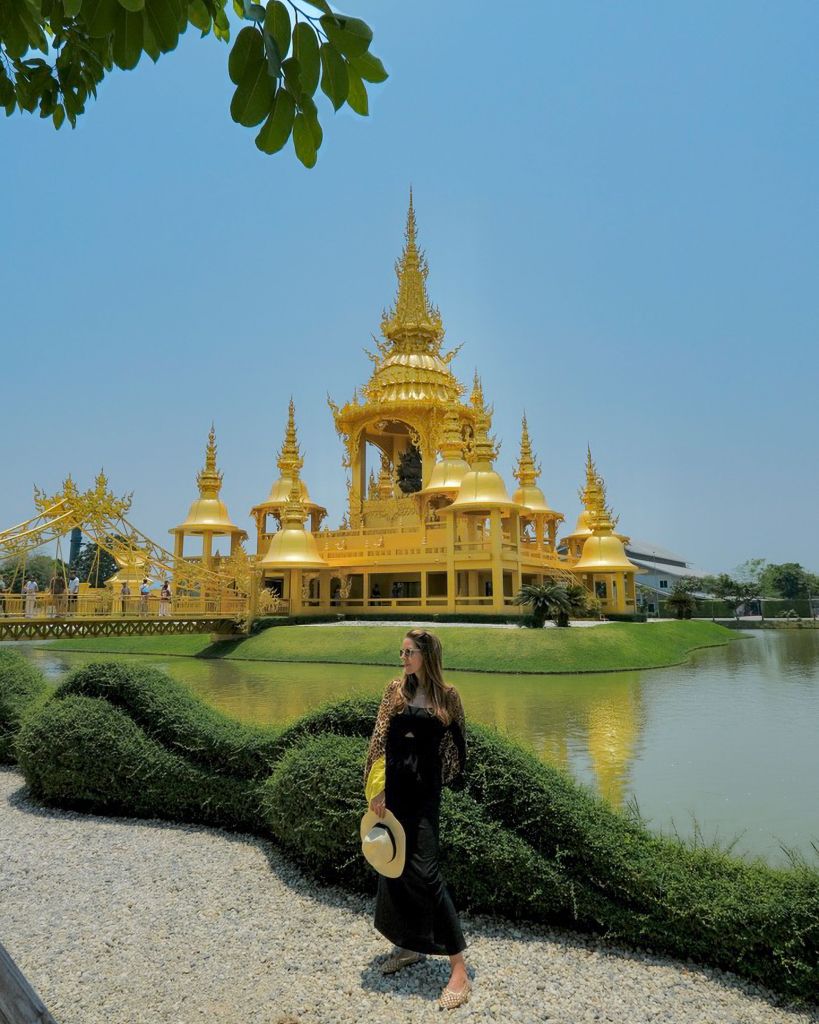 Woman in a black dress in front of the golden restroom building at the White Temple (Wat Rong Khun) in Chiang Rai, Thailand